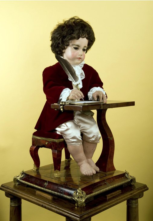 O autômato escritor de Jaquet-Droz sentado à escrivaninha, com a pena na mão
